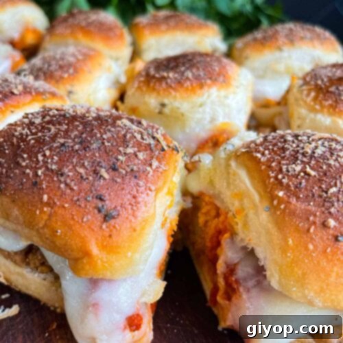 Cheesy Baked Chicken Parmesan Sliders 19 Chicken parmesan sliders on a wooden cutting board.