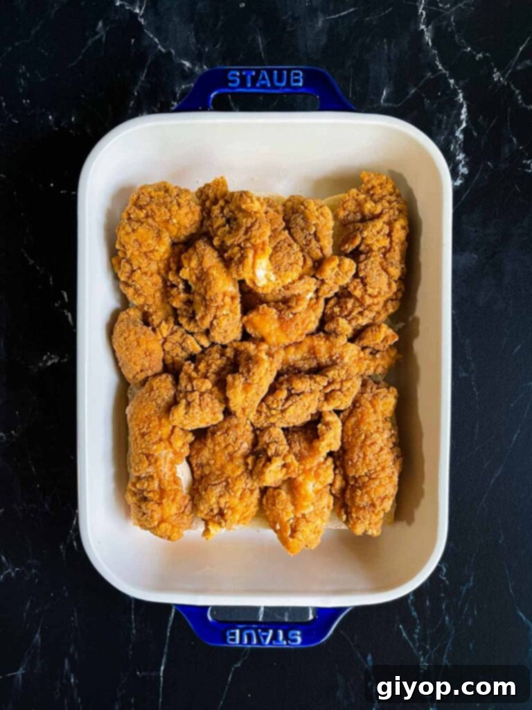 Cheesy Baked Chicken Parmesan Sliders 8 Cooked chicken tenders perfectly layered on the bottom slider rolls in a baking dish.