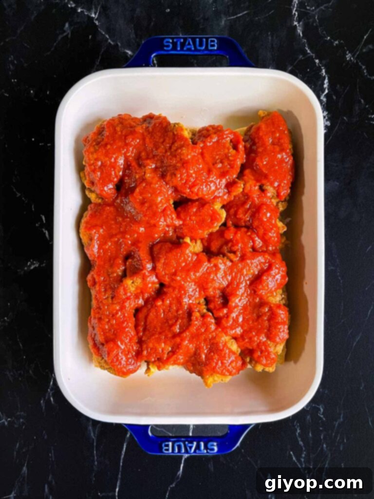 Cheesy Baked Chicken Parmesan Sliders 9 Marinara sauce spread evenly over the chicken layer on the sliders.