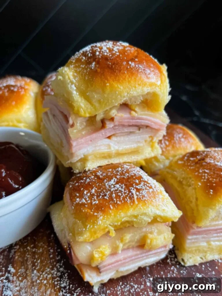 Monte Cristo sliders stacked up on a dark cutting board.