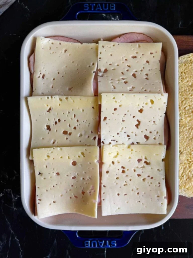 Swiss layered over slider rolls in a baking dish.