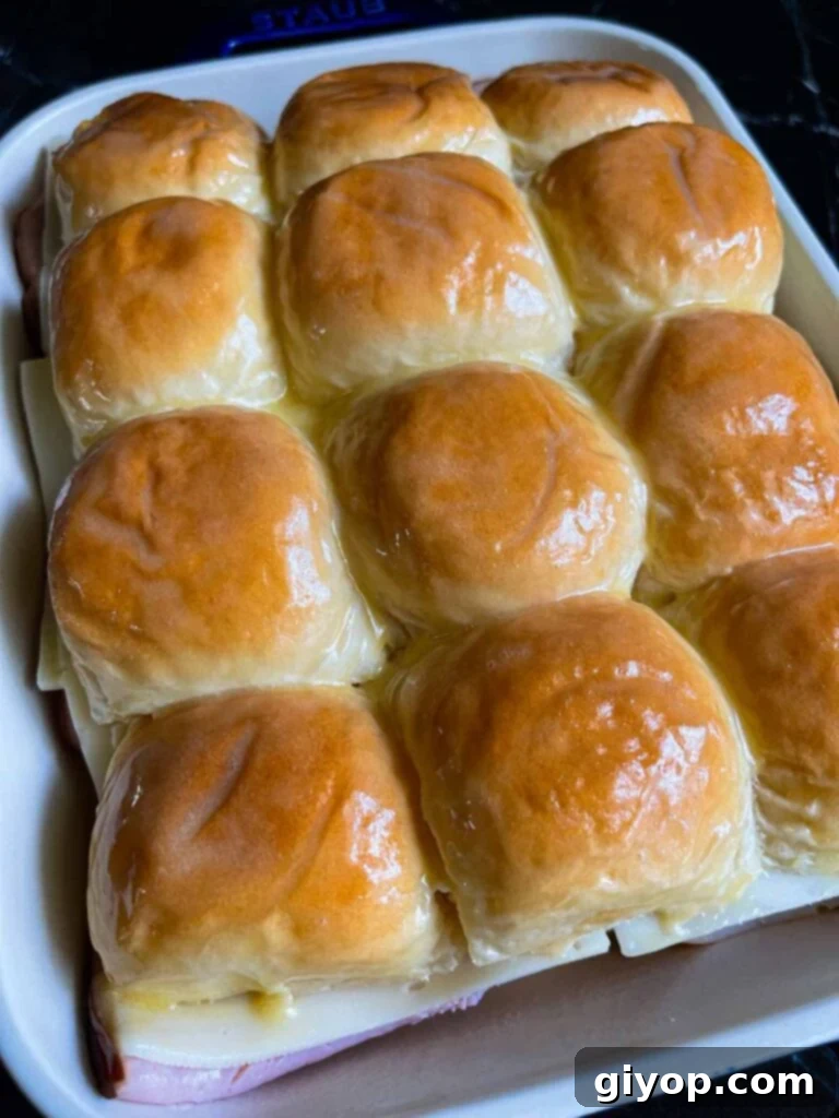 Monte Cristo sliders topped with egg wash in a baking dish.