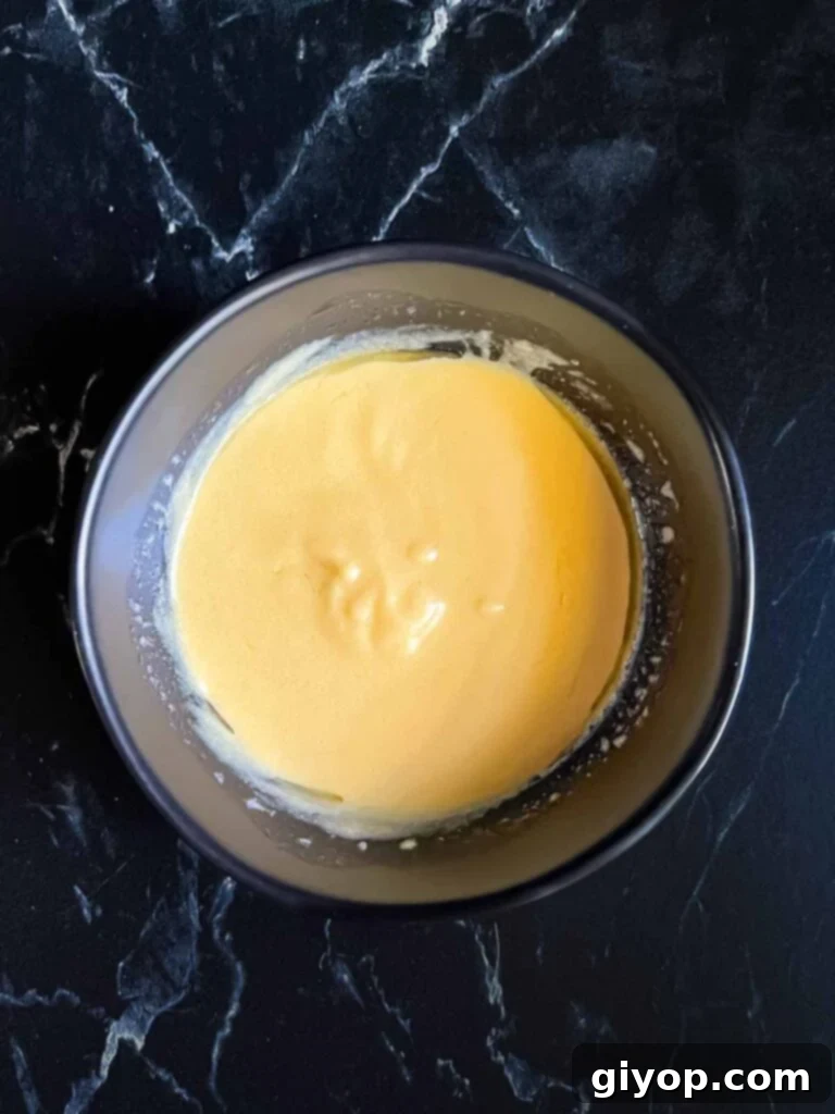 Dijon mustard sauce in a dark bowl.