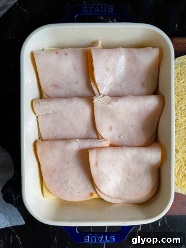 Turkey layered over slider rolls in a baking dish.