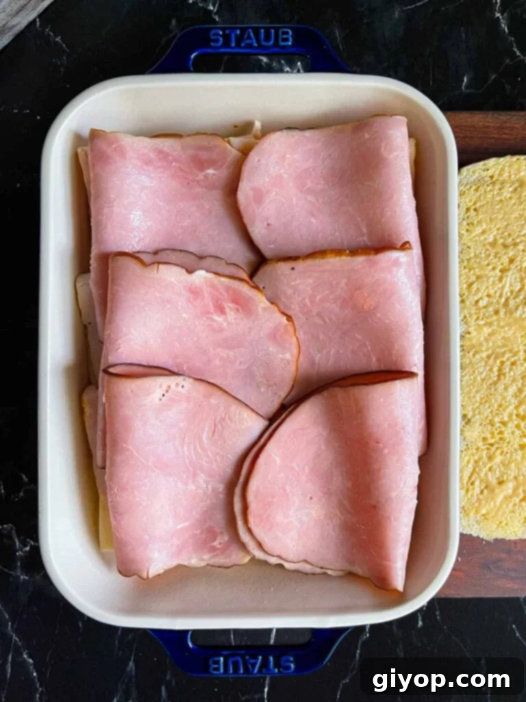 Ham layered over slider rolls in a baking dish.