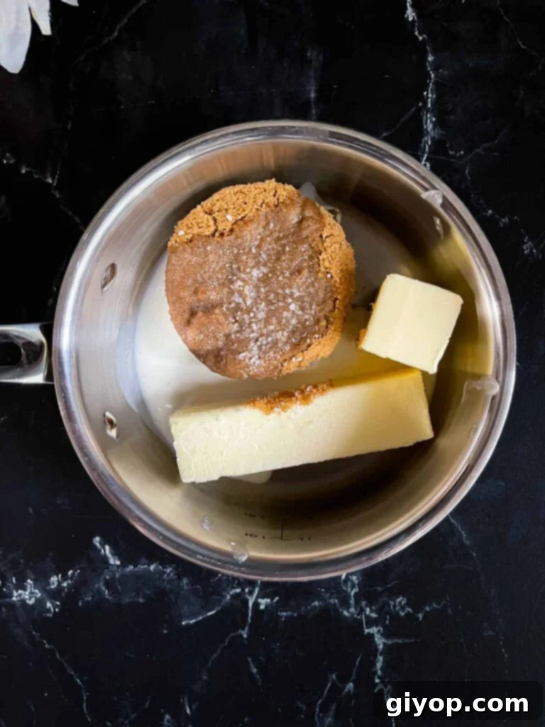 Brown sugar, butter, heavy cream, and kosher salt in a medium saucepan on a dark surface.