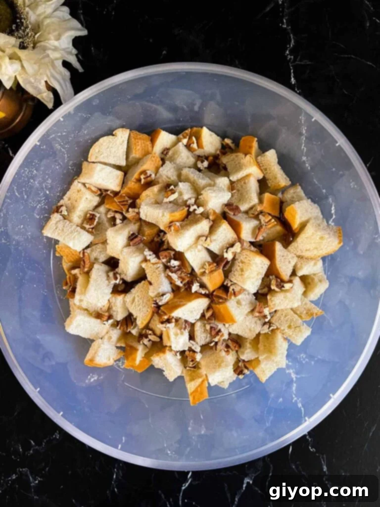 Decadent Pumpkin Bread Pudding with Salted Caramel Drizzle 5 Bread cubes and pecans in a large bowl on a dark surface.