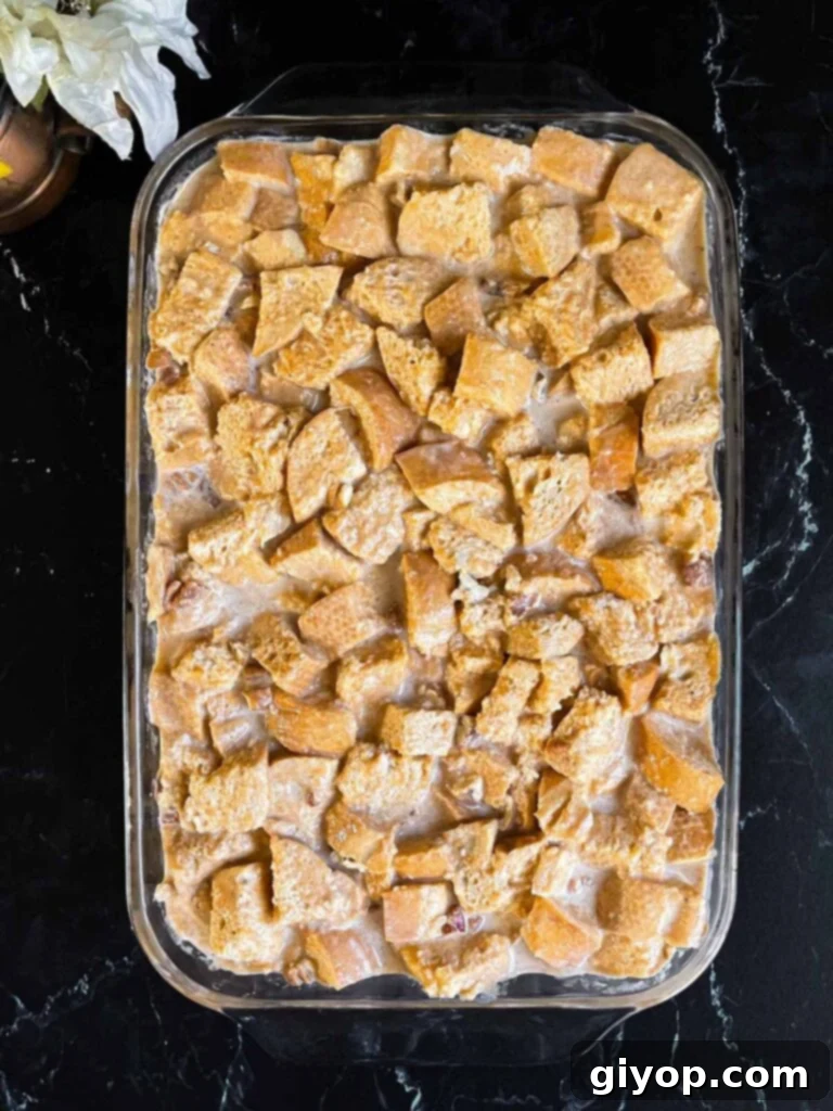 Decadent Pumpkin Bread Pudding with Salted Caramel Drizzle 8 Unbaked pumpkin bread pudding in a 9x13 baking dish on a dark surface.