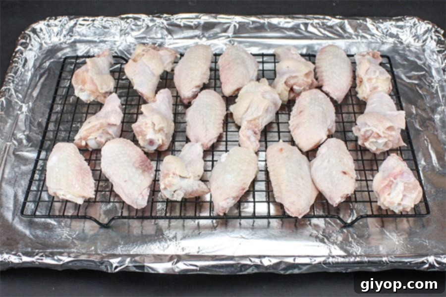 Chicken wings arranged on a wire rack over a foil-lined baking sheet, ready for baking.