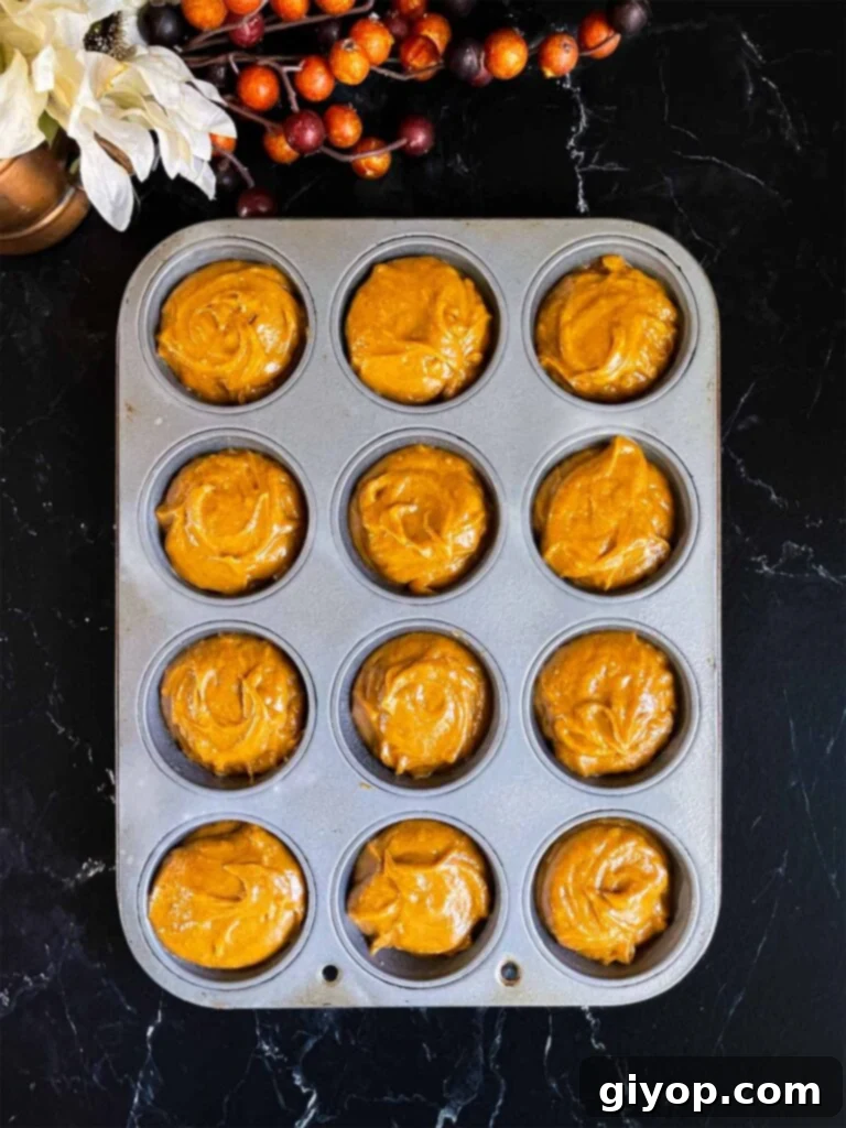 Sweet potato muffin batter divided into a 12 cup muffin tin.
