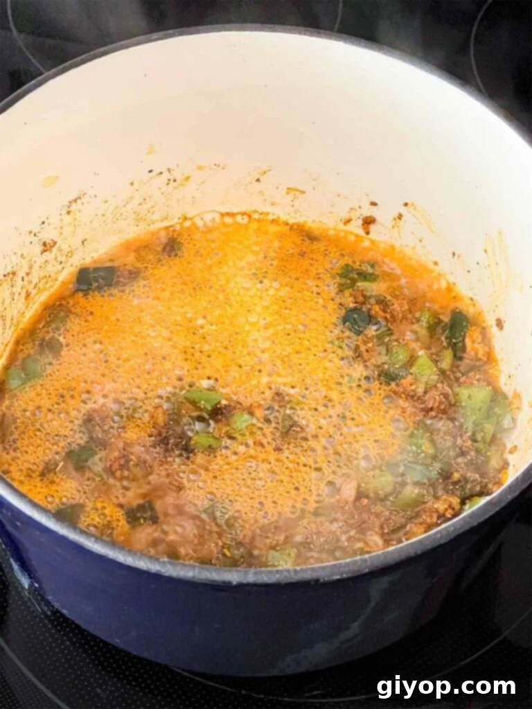 Beer added to cooked vegetables in a dutch oven.