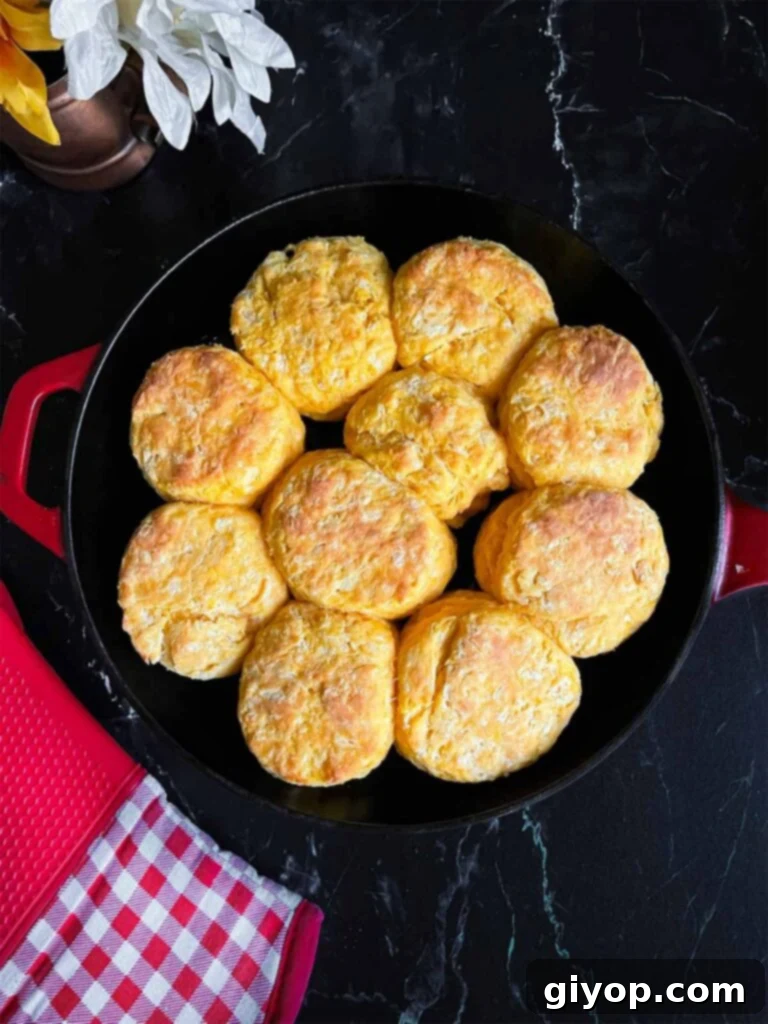 Baked sweet potato biscuits in a cast iron skillet on a dark surface.