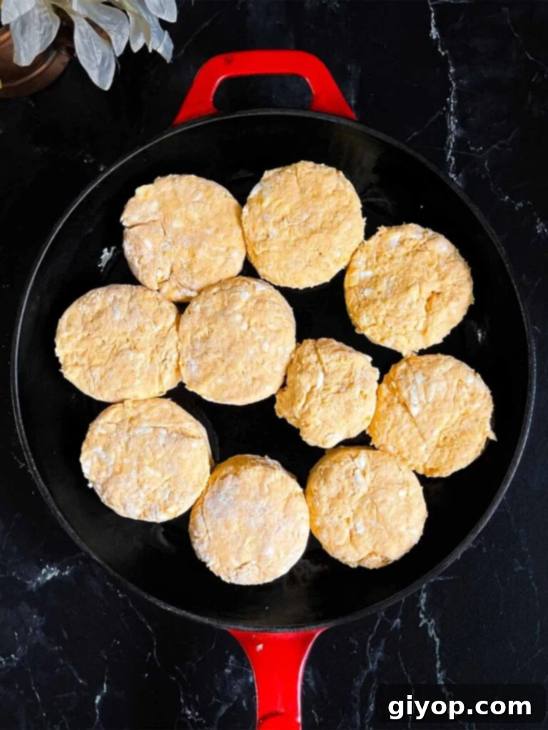 Unbaked sweet potato biscuits in a cast iron skillet on a dark surface.