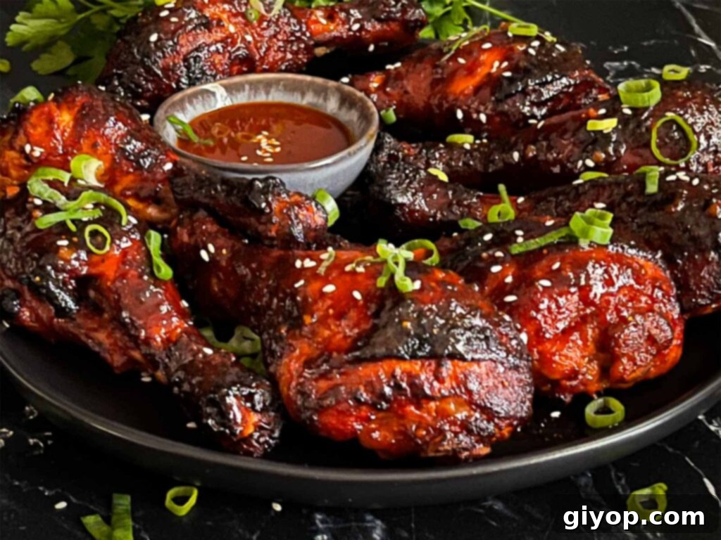 Smoky Gochujang Fire Chicken Legs 12 Smoked gochujang chicken legs on a dark plate.