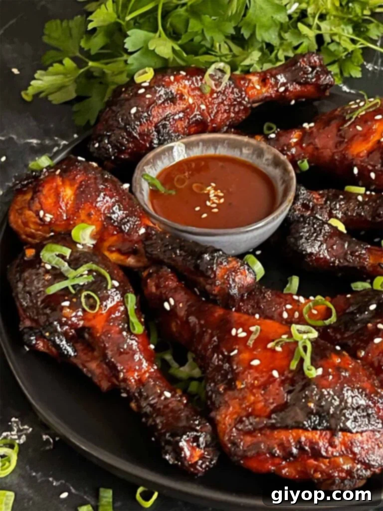 Smoky Gochujang Fire Chicken Legs 3 Smoked gochujang chicken legs on a dark plate.