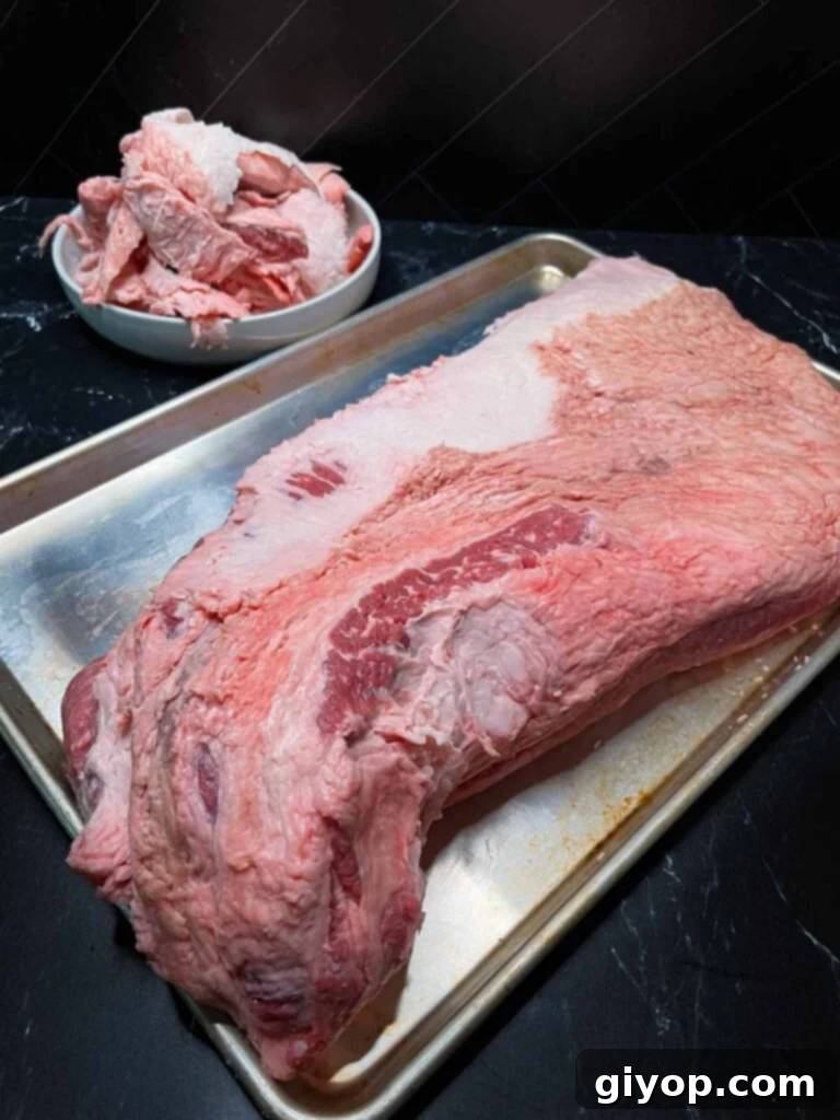 A trimmed brisket on a sheet pan with scraps in the background.