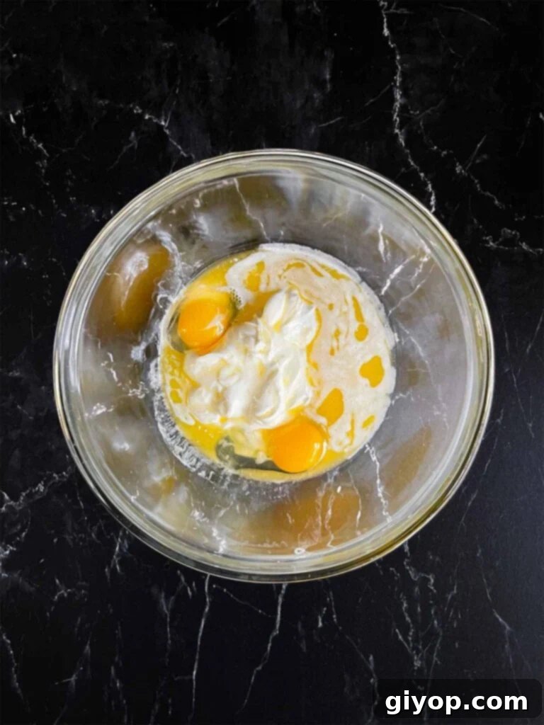 Corn casserole wet ingredients in a glass bowl.