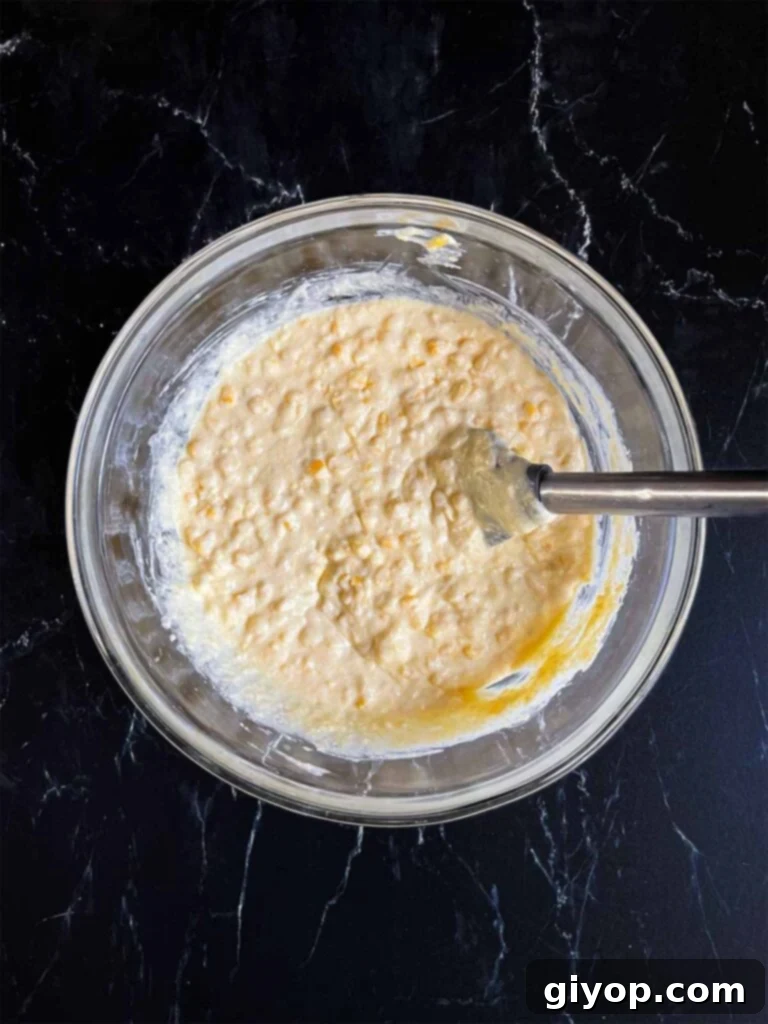Corn casserole batter mixed in a glass mixing bowl.
