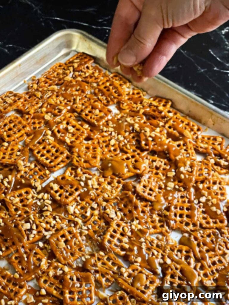 Sprinkling toffee bits over the warm drizzled toffee on the pretzels.