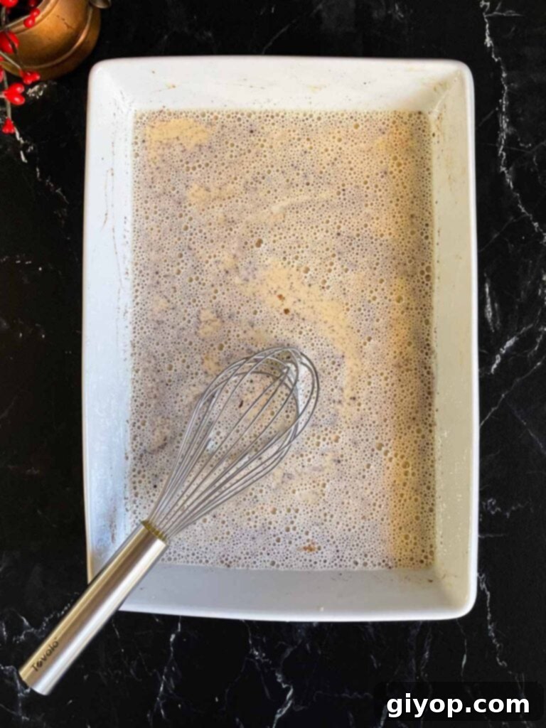 All the panettone French toast egg mixture ingredients whisked together in a shallow baking dish, ready for dipping.