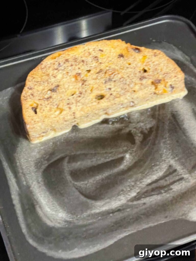 A single slice of panettone French toast perfectly cooking on a buttered griddle, achieving a golden hue.