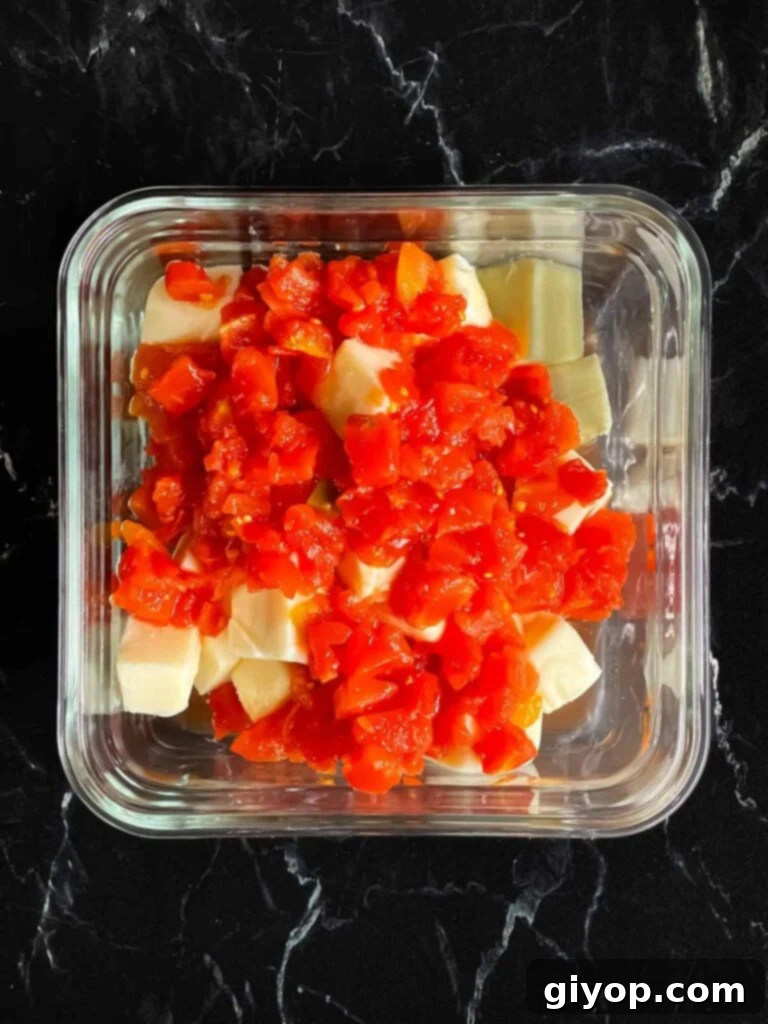 Cubed velveeta cheese with Rotel in a glass container.