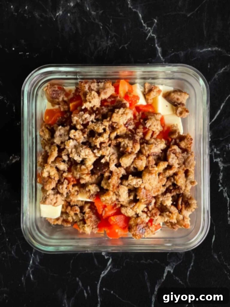 Velveeta cheese, Rotel, and browned sausage together in a glass bowl.