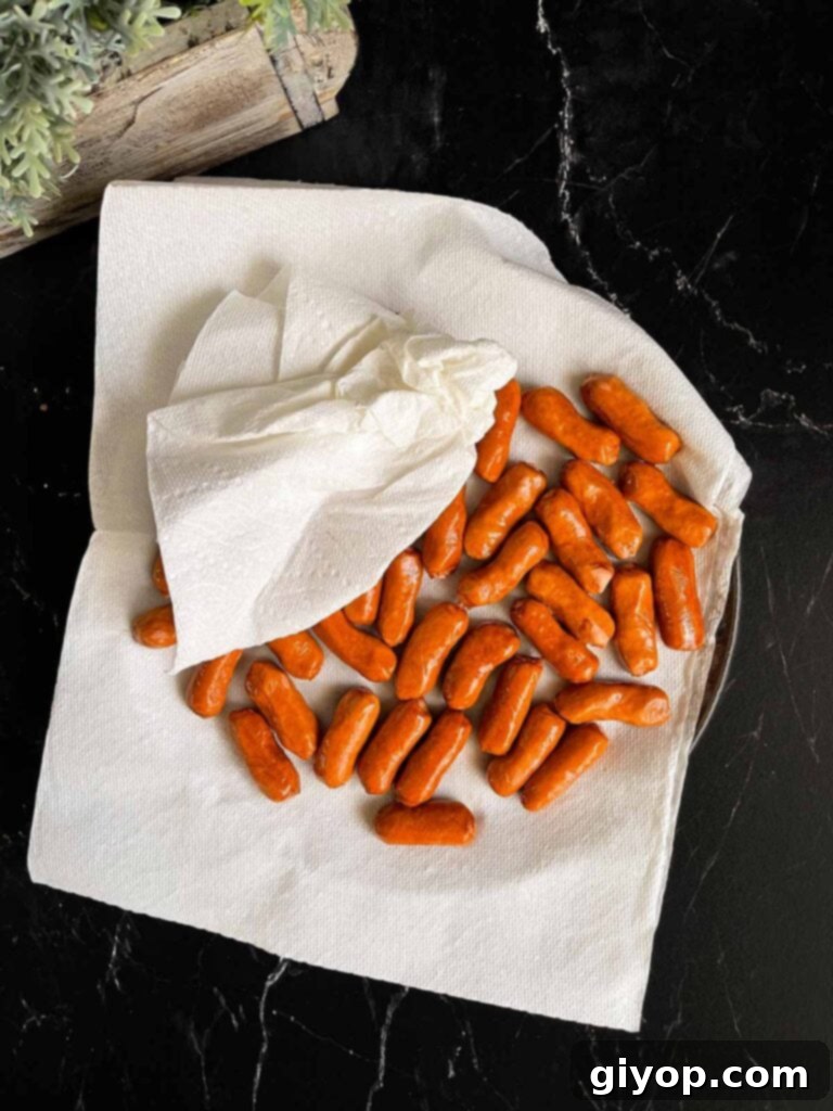 Pigs in Fluffy Biscuits 4 Cocktail sausages on a paper towel lined plate.