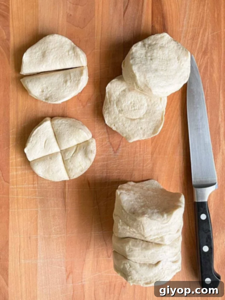 Pigs in Fluffy Biscuits 5 Refrigerated biscuit dough cut into quarters on a wooden board.