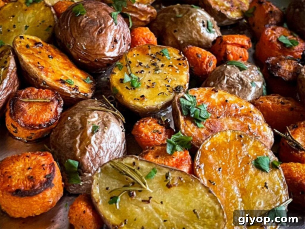 Golden brown roasted potatoes and carrots on a baking sheet, ready to be served.