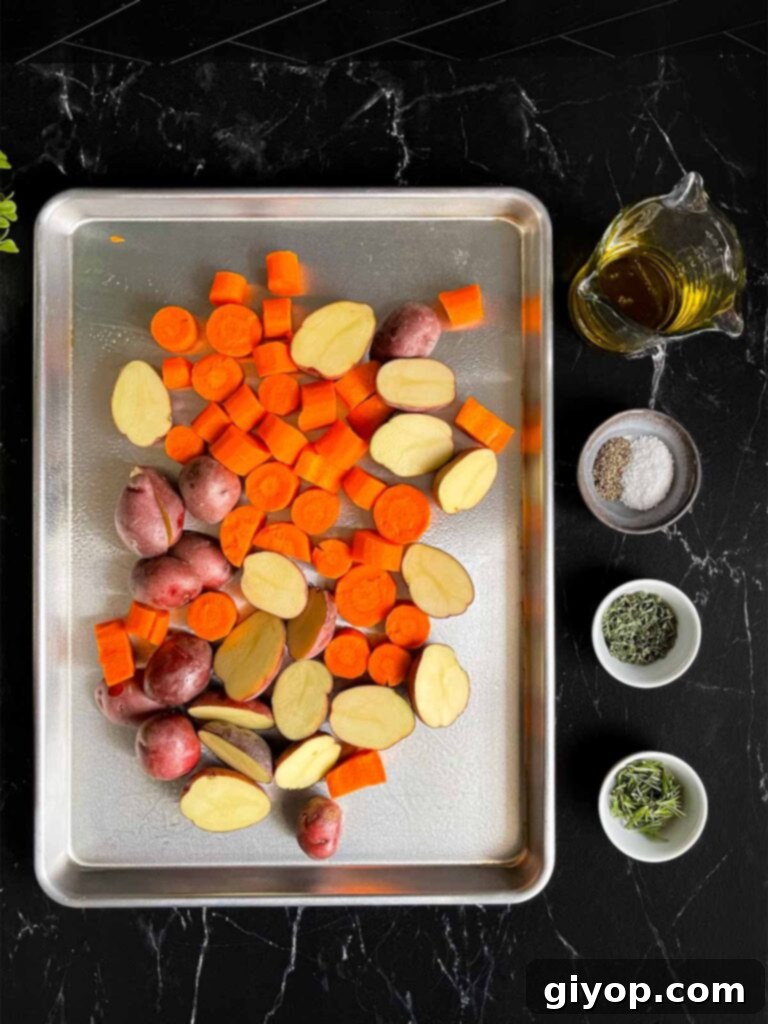 Raw potatoes and carrots on a baking sheet, with small ramekins of seasonings next to the pan, ready to be mixed.