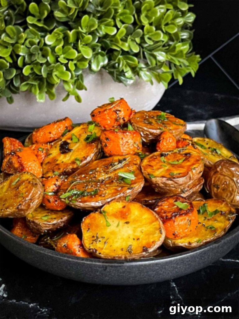 A close-up of roasted potatoes and carrots served in a dark ceramic bowl, ready to be enjoyed.