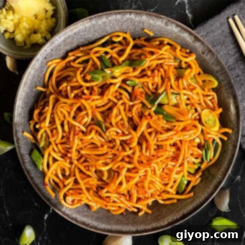 Spicy garlic noodles in a dark bowl.