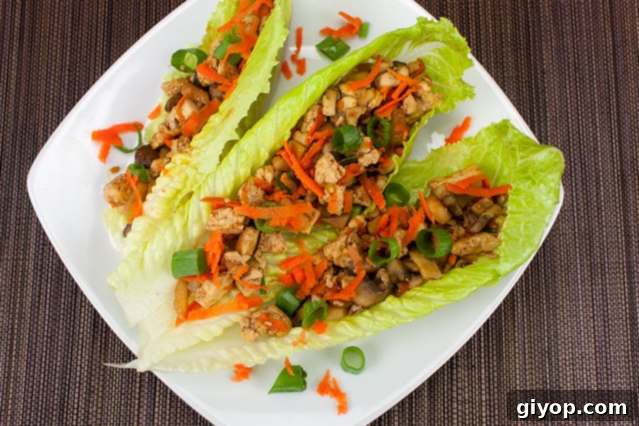 Crispy tofu and mushroom vegetarian lettuce wraps served on fresh lettuce leaves with garnishes.