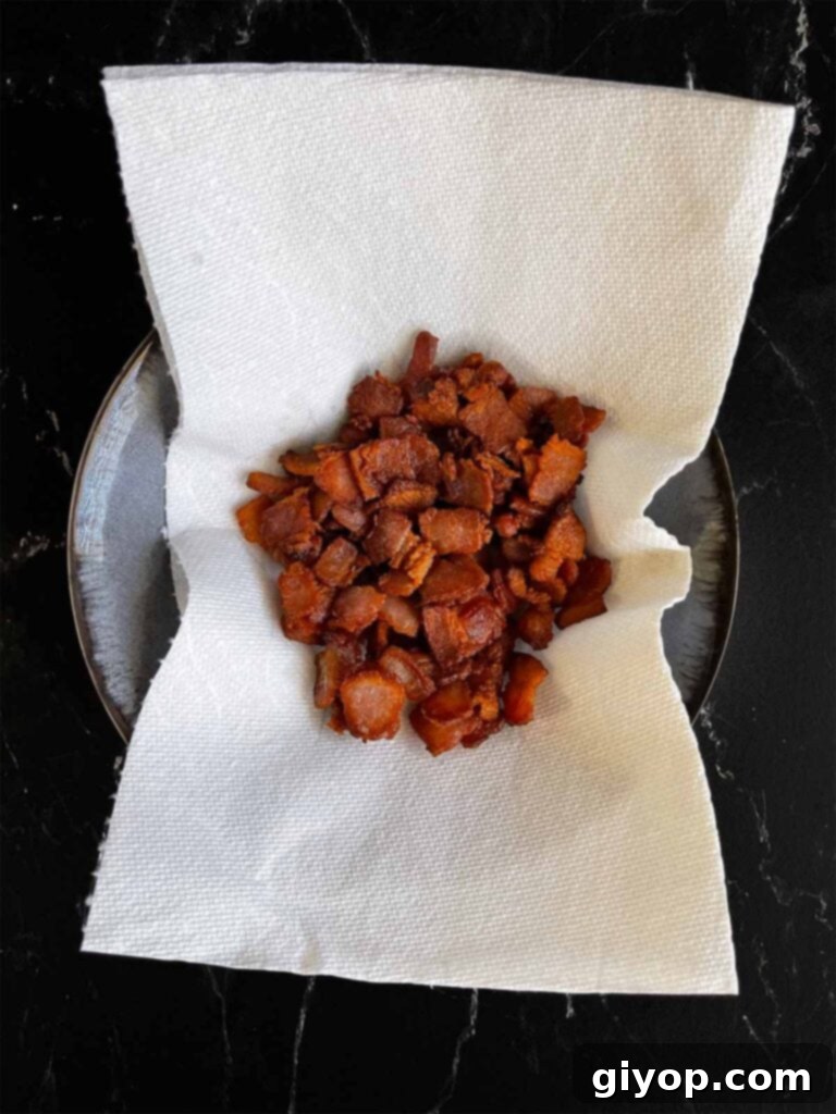 Cooked bacon draining on a paper towel in a bowl.