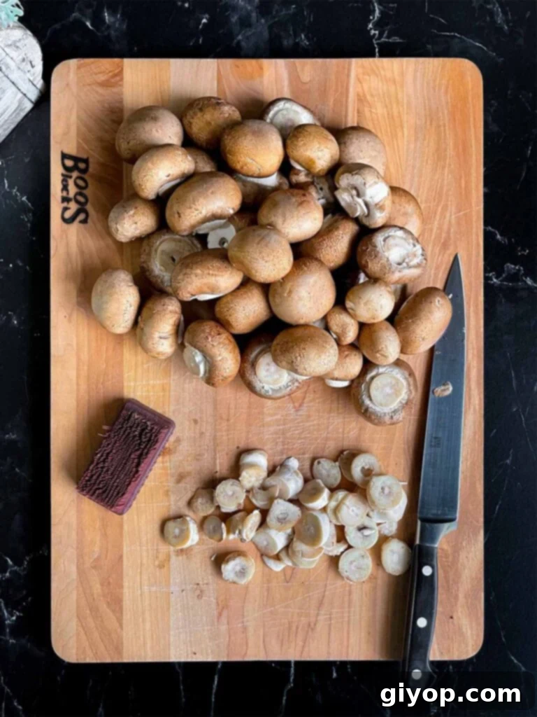 Cremini (baby bella) mushrooms cleaned and trimmed on a wooden board.