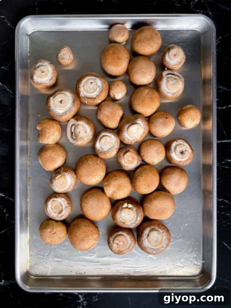 Cleaned Cremini mushrooms on an oiled baking sheet.