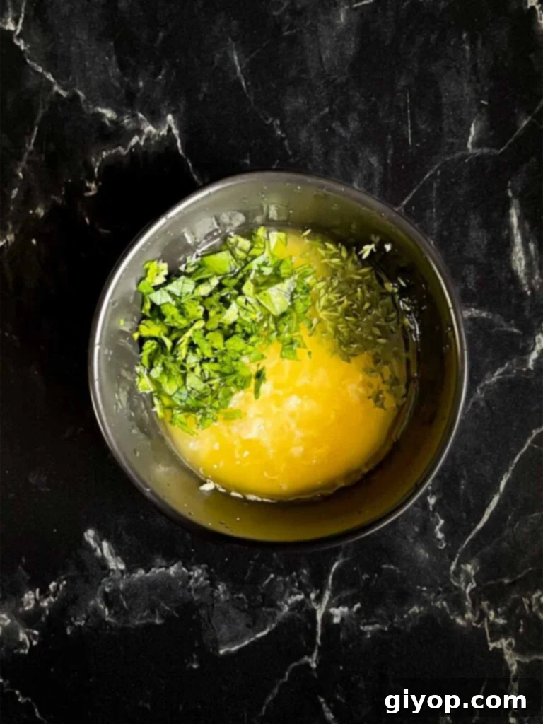 Garlic butter mixture ingredients in a dark bowl on a dark surface.