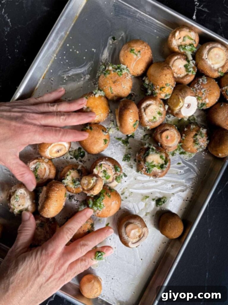 Mushrooms being tossed on the baking sheet with the garlic butter mixture.