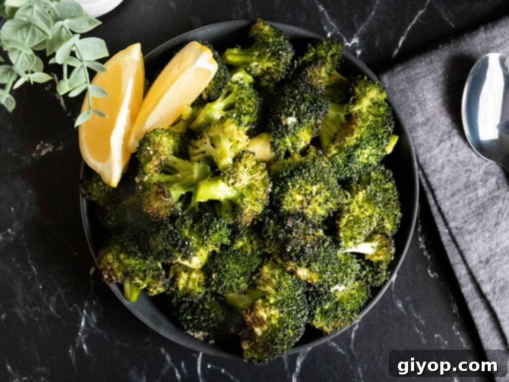 Crispy Roasted Broccoli 2 Perfectly roasted broccoli with a lemon wedge garnish in a dark bowl, ready to serve.