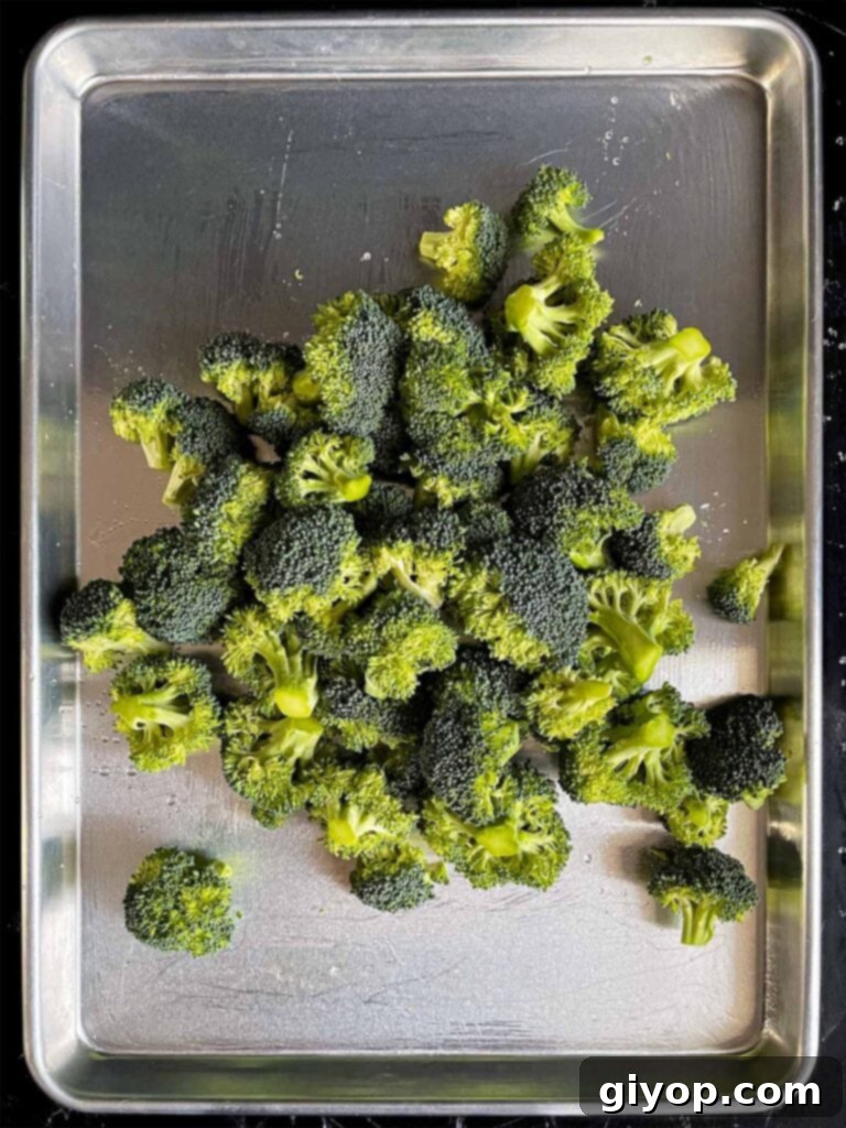 Crispy Roasted Broccoli 4 Raw broccoli florets spread out on a baking sheet, ready for seasoning.