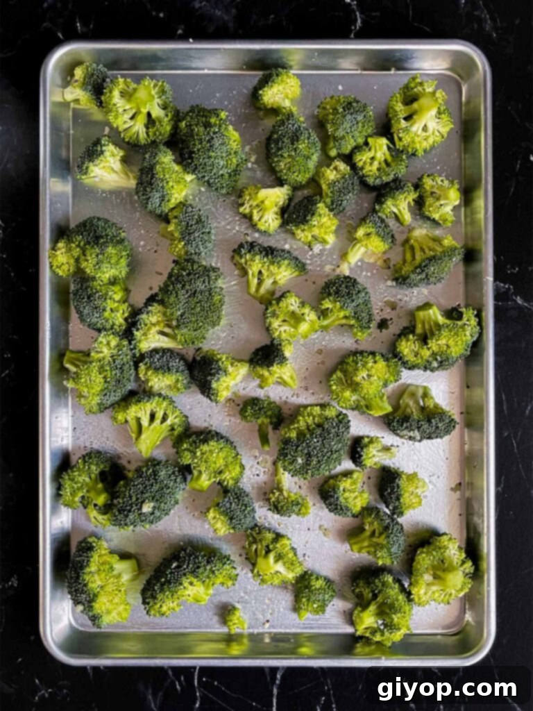 Crispy Roasted Broccoli 5 Broccoli florets evenly seasoned with olive oil, garlic, salt, and pepper on a baking sheet.