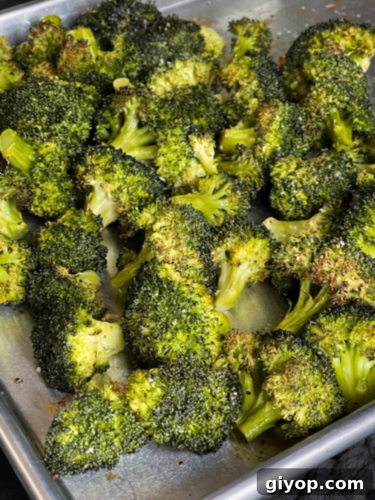 Crispy Roasted Broccoli 6 Perfectly roasted broccoli on a baking sheet, displaying golden-brown edges and tender stalks.