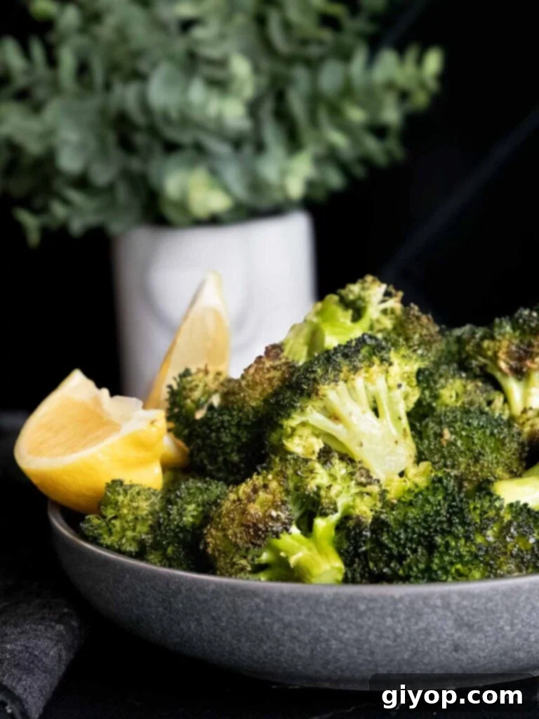 Crispy Roasted Broccoli 7 Roasted broccoli with a lemon wedge garnish in a dark bowl, ready for serving.