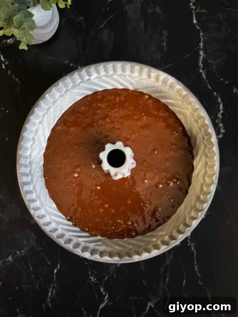 Chocolate bundt cake batter poured evenly into a prepared bundt pan on a dark surface, ready for the oven.