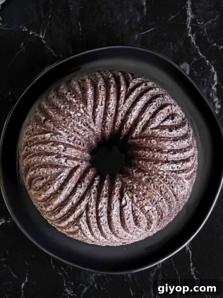The chocolate bundt cake perfectly inverted onto a dark serving plate from the bundt pan, ready for ganache.