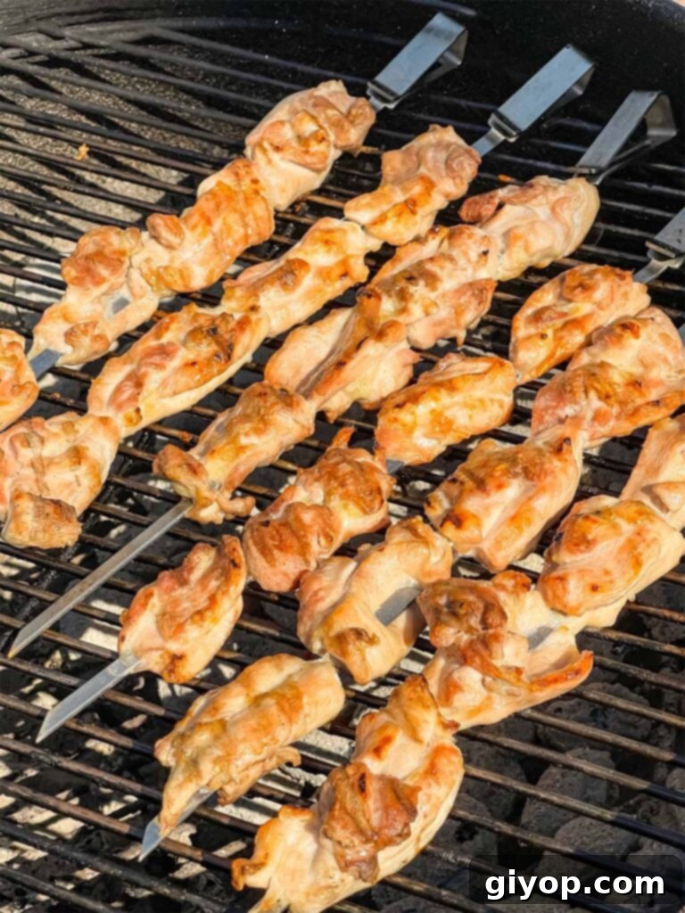 Skewered chicken thighs cooking on a grill.