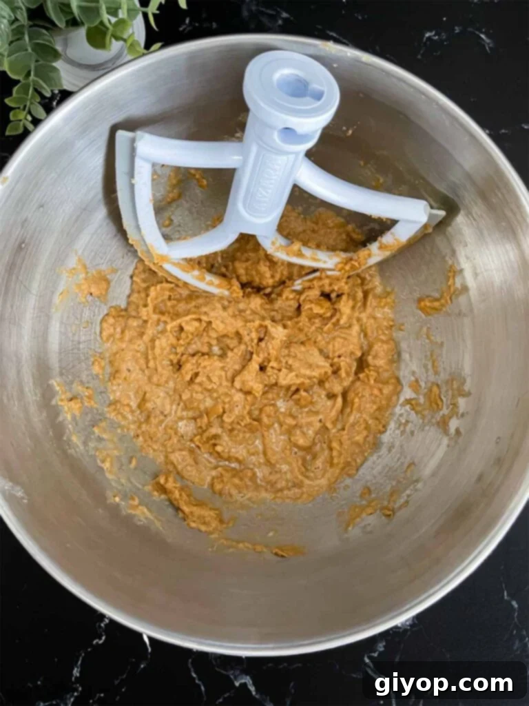 Chewy Oatmeal Fudge Bars 4 Wet ingredients for oatmeal fudge bars, including beaten butter, brown sugar, eggs, and vanilla, perfectly mixed in a metal mixing bowl.