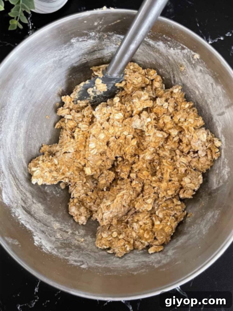 Chewy Oatmeal Fudge Bars 5 Hearty oatmeal cookie dough, featuring old-fashioned oats and perfectly combined wet and dry ingredients, ready for baking in a metal mixing bowl.