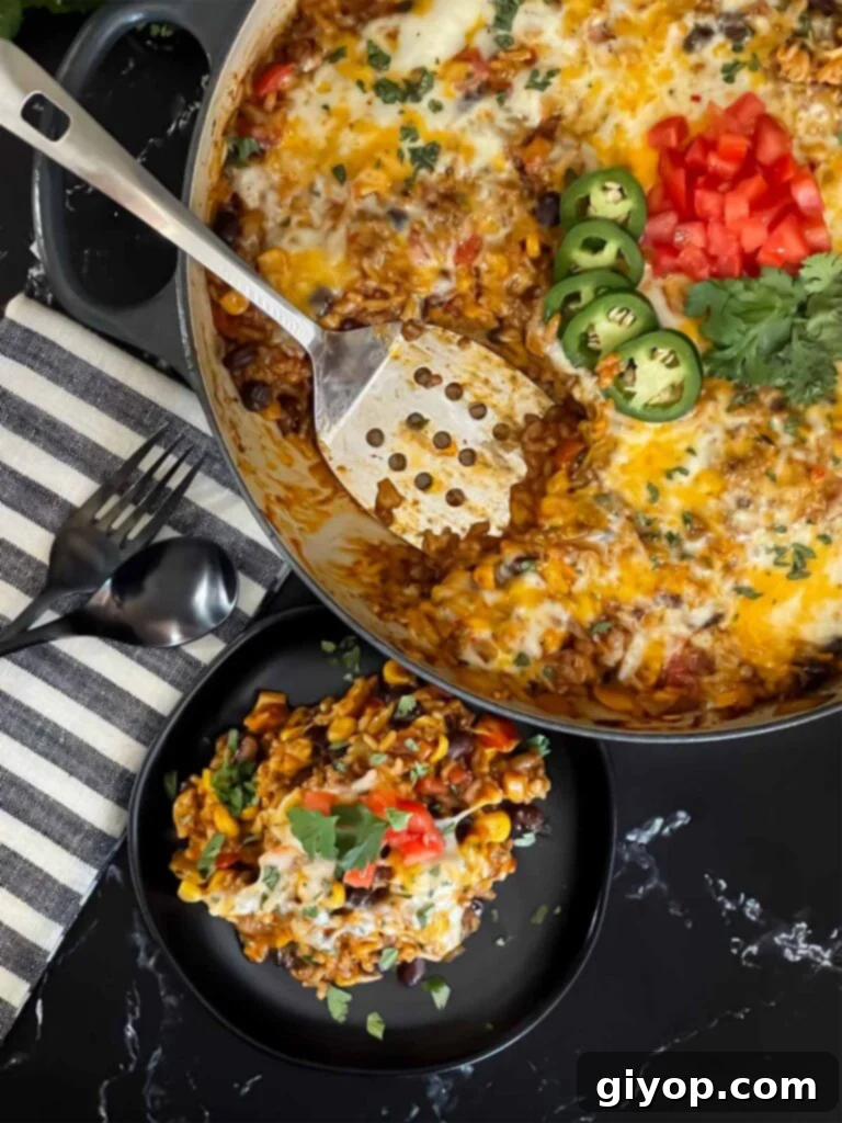 Close-up of a serving of Mexican ground beef with rice, showing melted cheese and fresh garnishes.